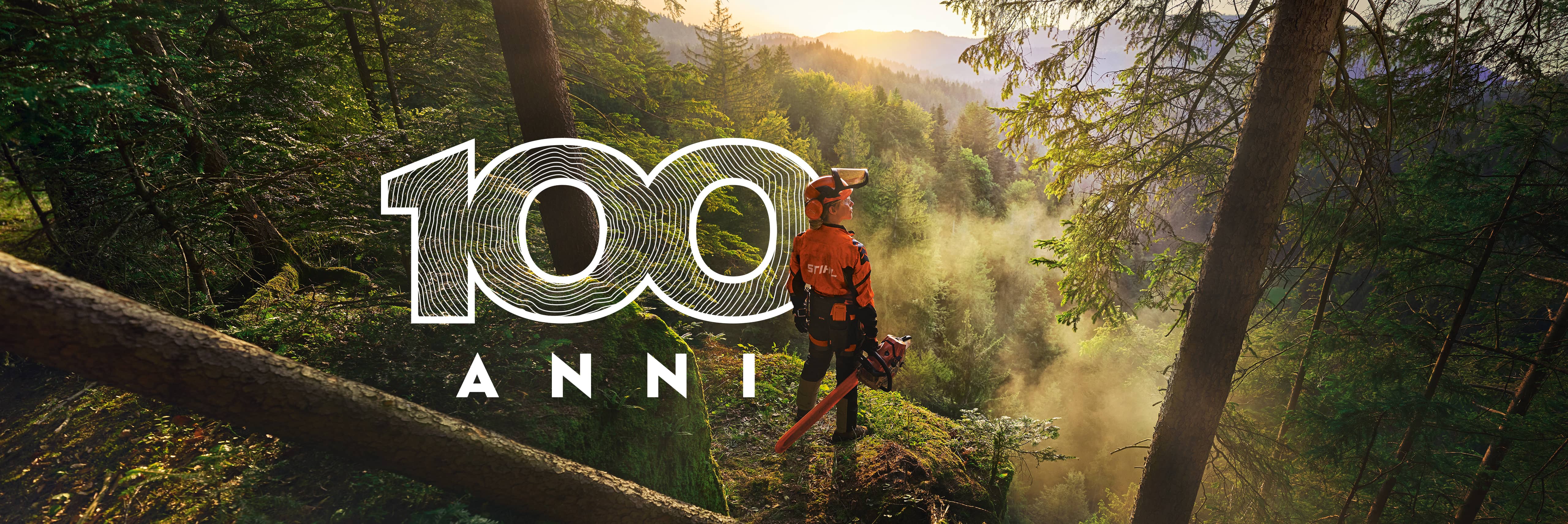 Una donna è in piedi sul bordo di una scogliera in una foresta di un verde saturo. Indossa l'abbigliamento da lavoro arancione STIHL, la cuffia ADVANCE ProCom e tiene in mano una motosega STIHL MS.